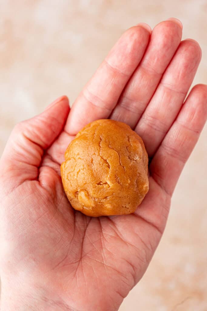 hand holding a stuffed peanut butter cookie dough ball