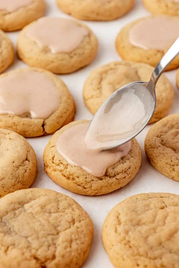 spoon spreading glaze on top of a cookie