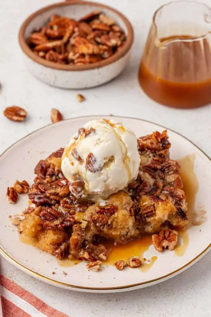 a scoop of ice cream on top of a serving of pecan cobbler