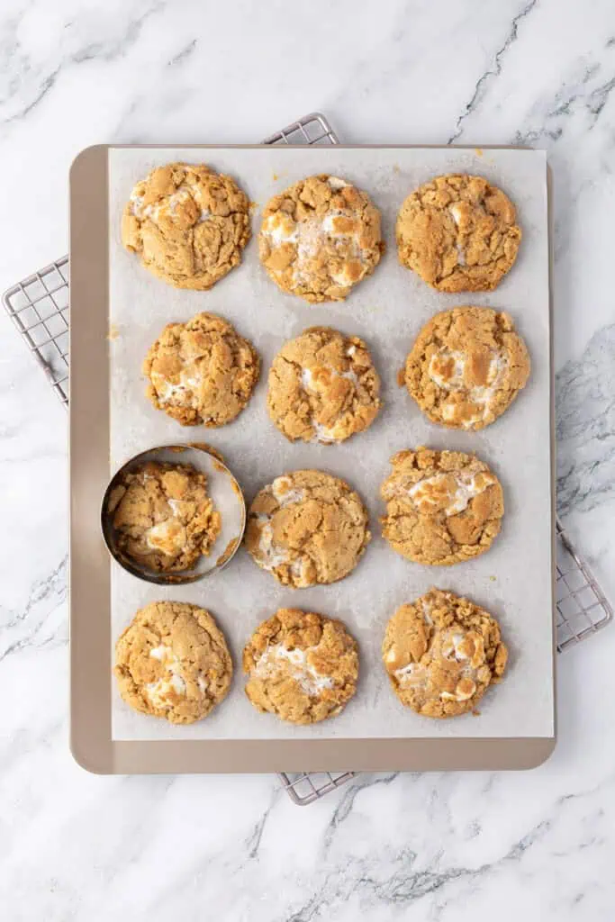 cookies baked on a cookie sheet with a round cookie cutter re-shaping them