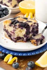 slice of blueberry cake with a forkful missing on a plate