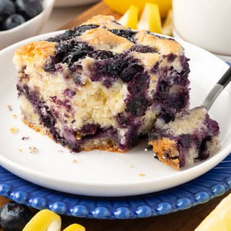 slice of blueberry cake with a forkful missing on a plate