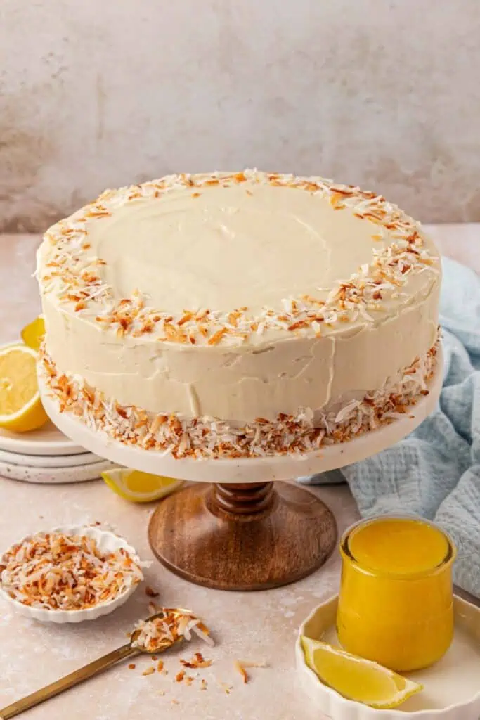 whole lemon coconut cake frosted and decorated on a cake stand
