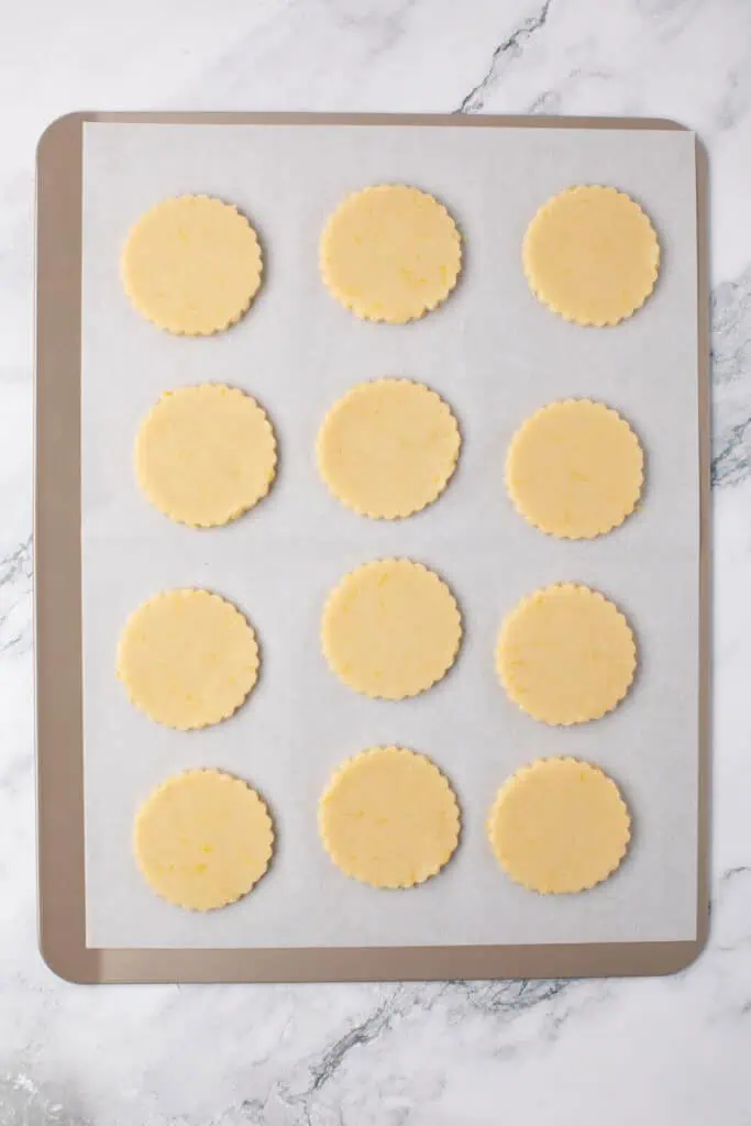 twelve cookie dough rounds on a cookie sheet