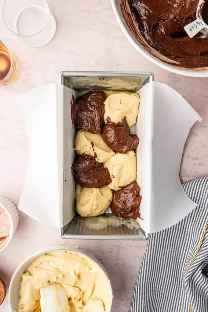 vanilla and chocolate batter dolloped into the loaf pan