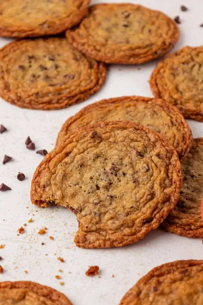 a thin and crispy chocolate chip cookie with a bite taken out of it