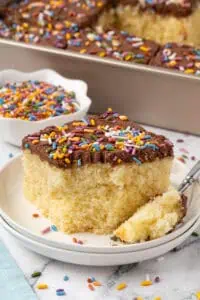 slice of yellow sheet cake with chocolate frosting on a plate with a fork