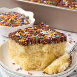 slice of yellow sheet cake with chocolate frosting on a plate with a fork