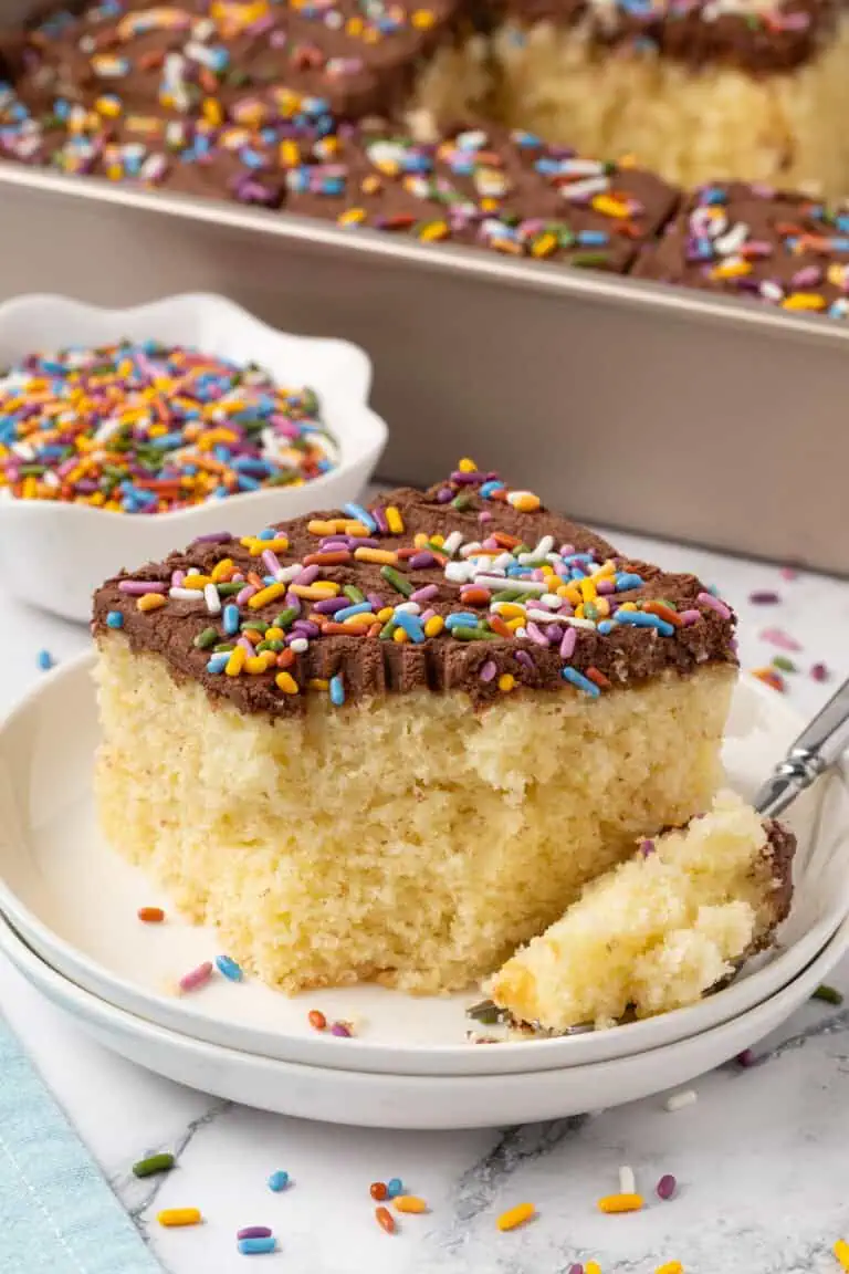 slice of yellow sheet cake with chocolate frosting on a plate with a fork