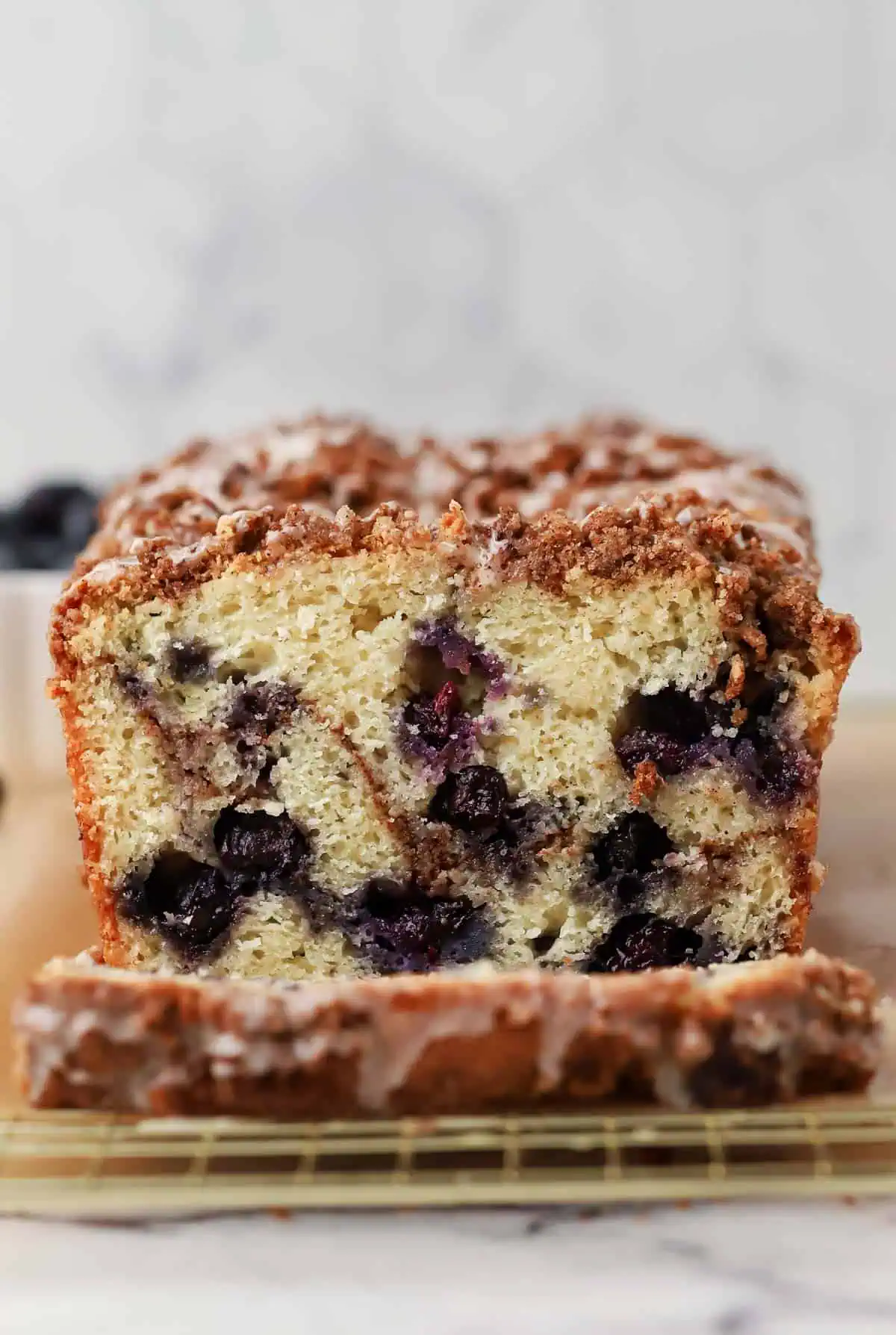 blueberry cinnamon bread loaf cut in half on a wire rack