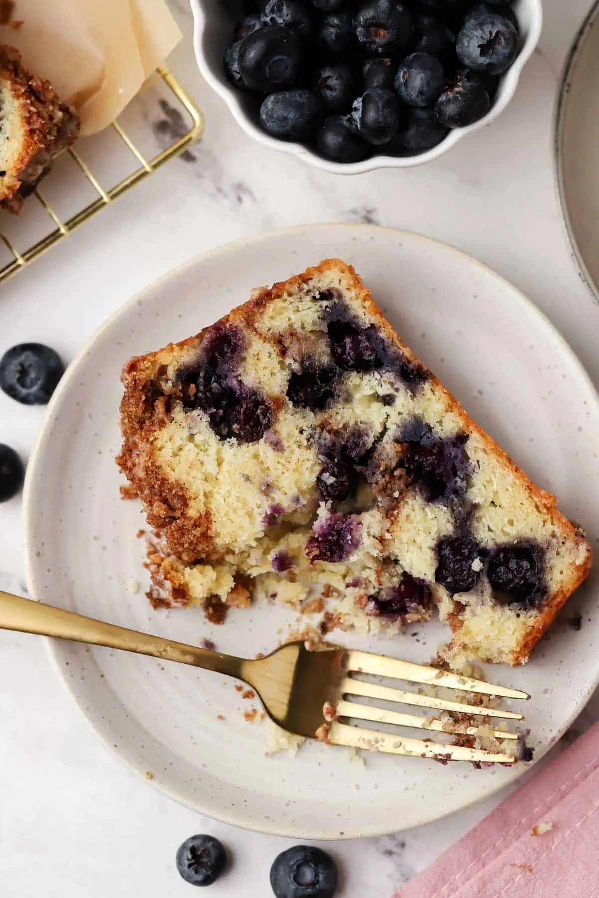 a slice of blueberry cinnamon bread with a forkful missing, on a plate with a fork