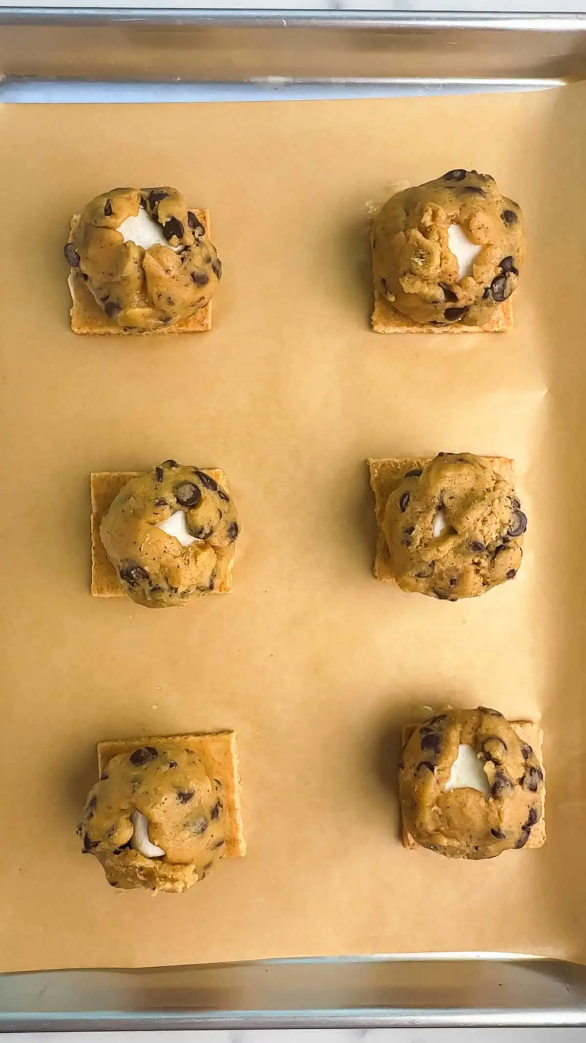 six cookie dough balls on a cookie sheet