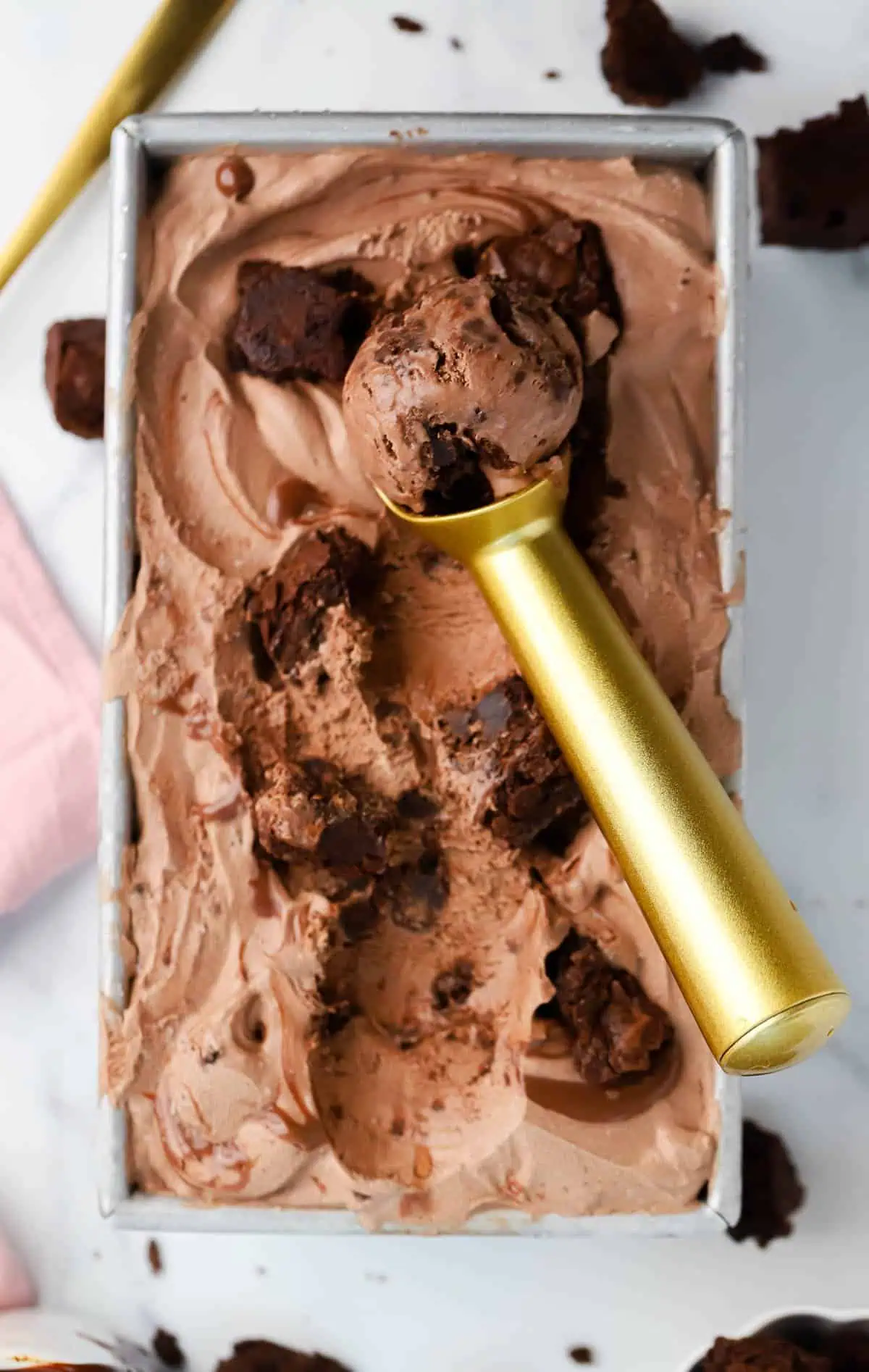a loaf pan of brownie fudge ice cream with an ice cream scoop in it