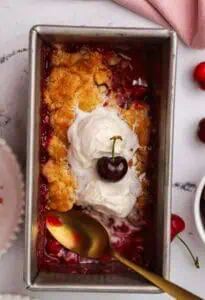 small batch cherry cobbler in a loaf pan topped with ice cream