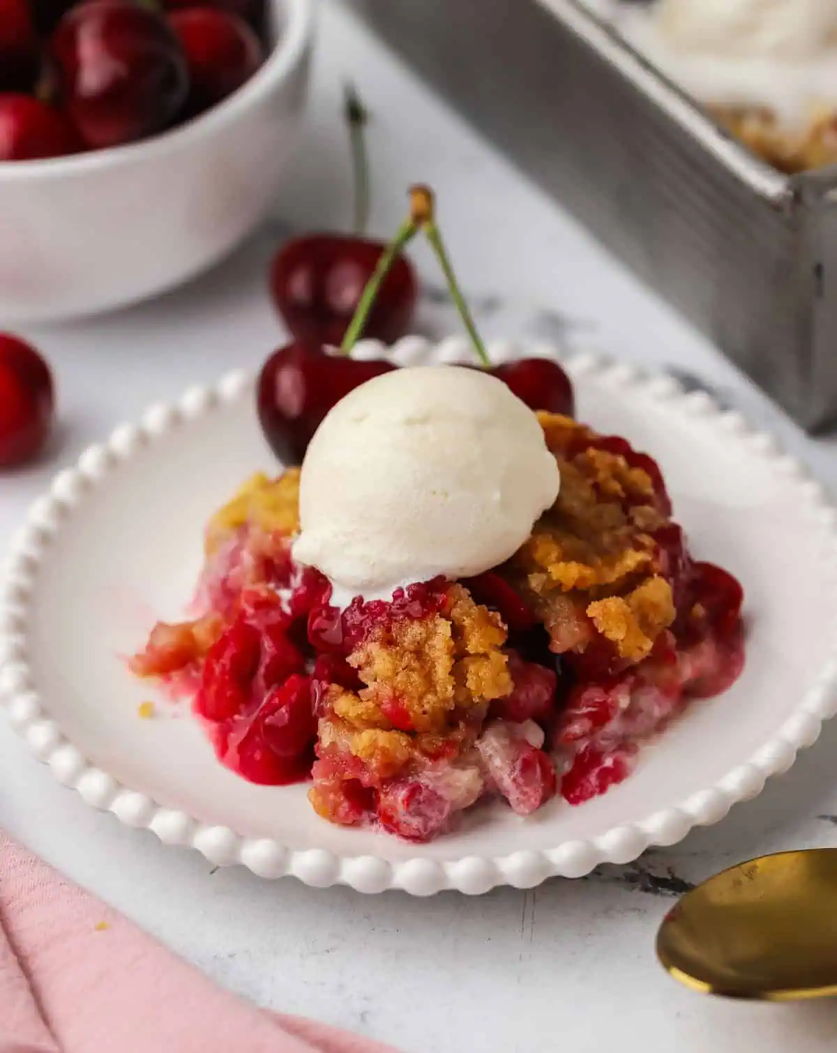 a plate of cherry cobbler topped with ice cream