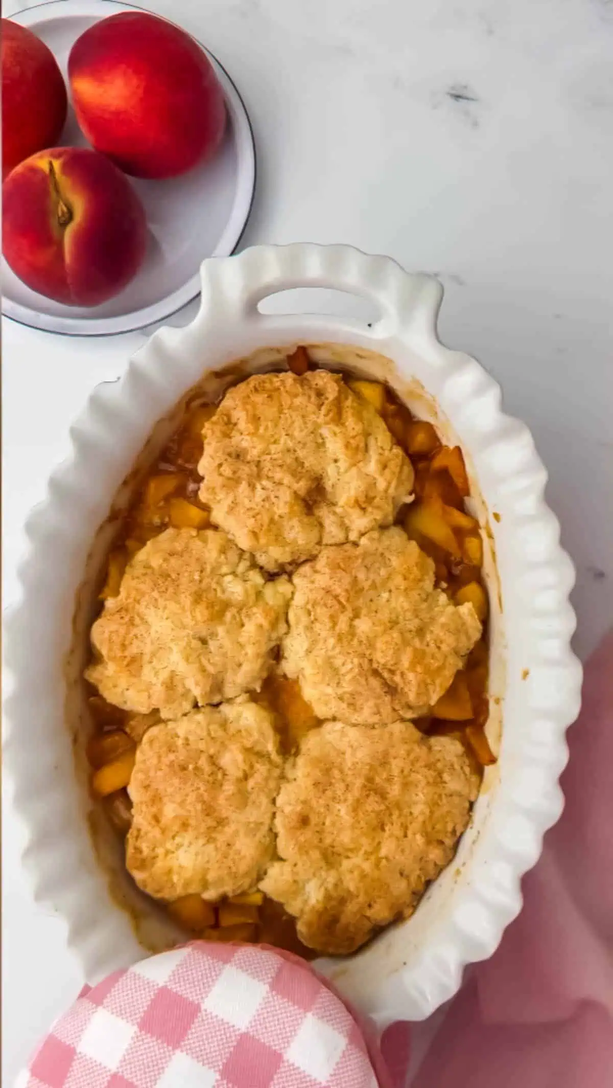 oven mitt holding a baked peach cobbler