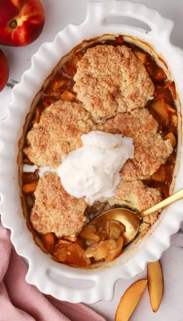 a dish of peach cobbler with a spoon in it