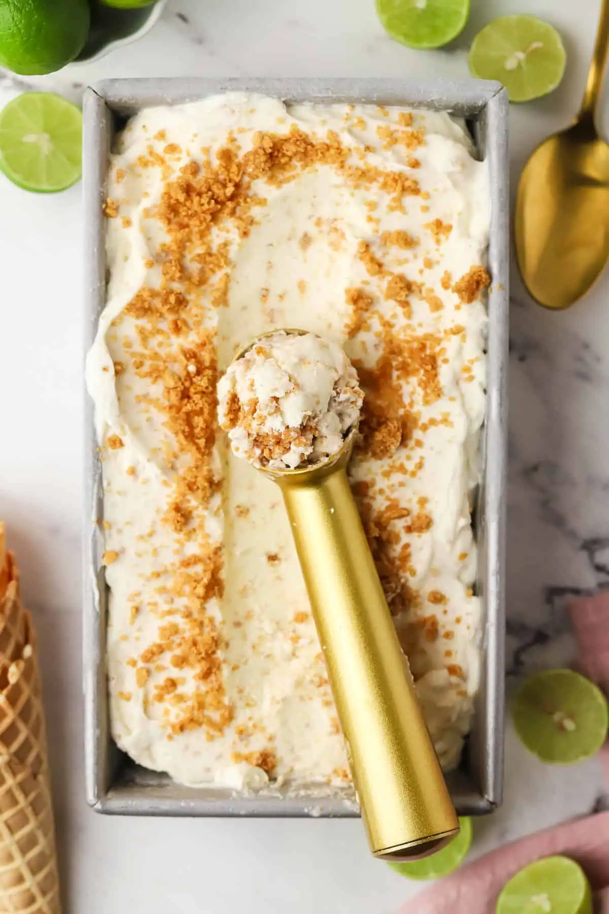 a loaf pan of key lime pie ice cream with an ice cream scoop in it
