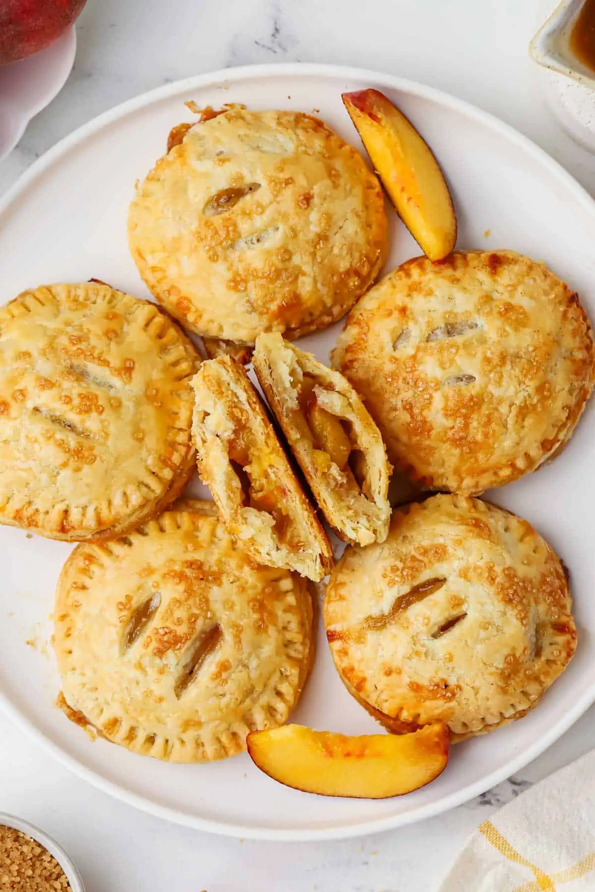 peach hand pie broken in half, on a plate with more pies