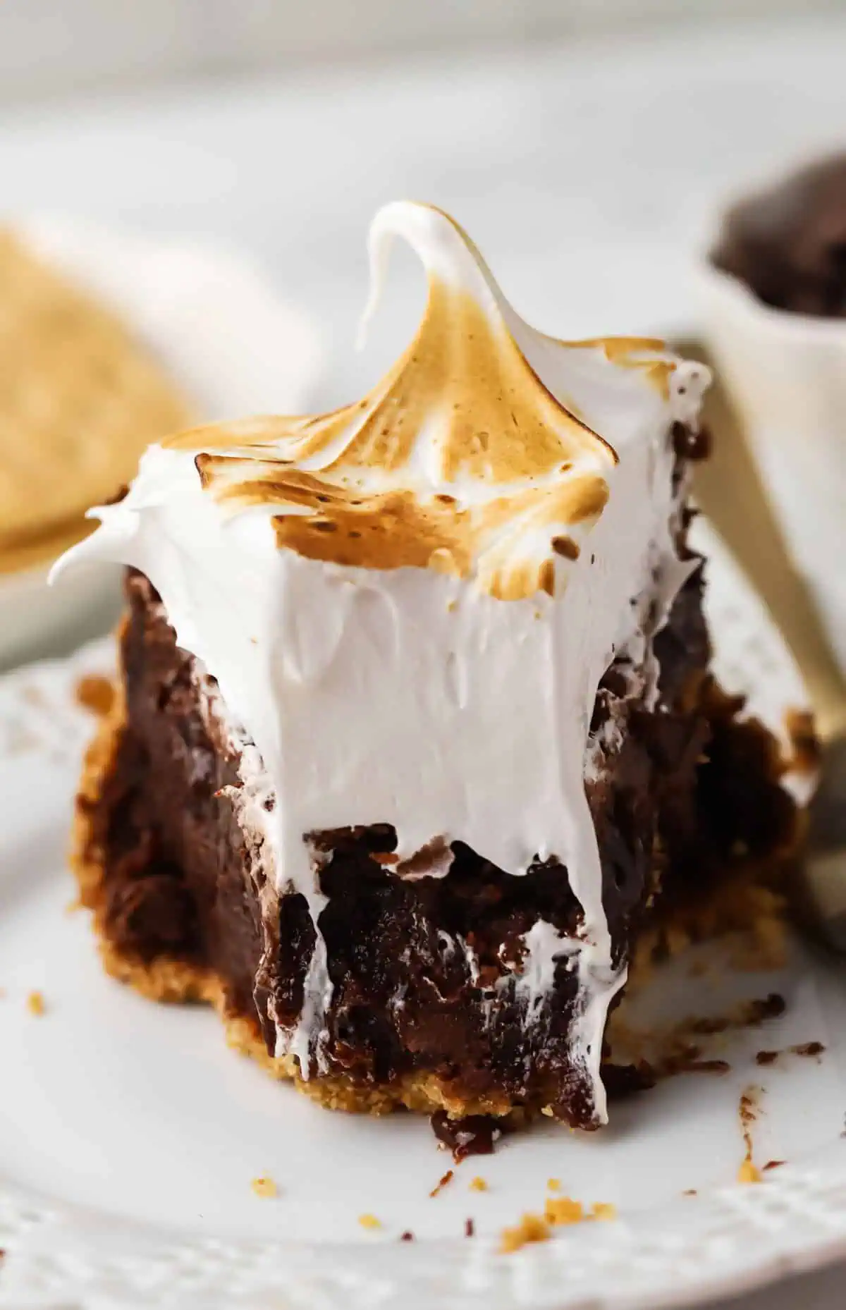 slice of s'mores brownie pie on a plate with a forkful missing