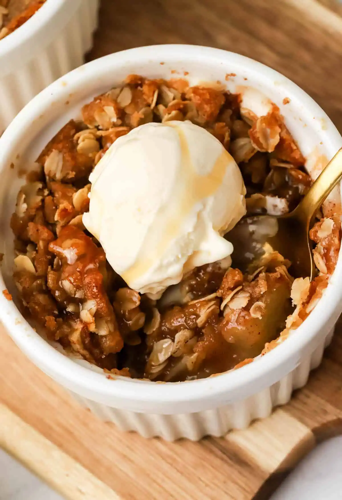 apple crisp ramekin topped with ice cream and a spoon in it