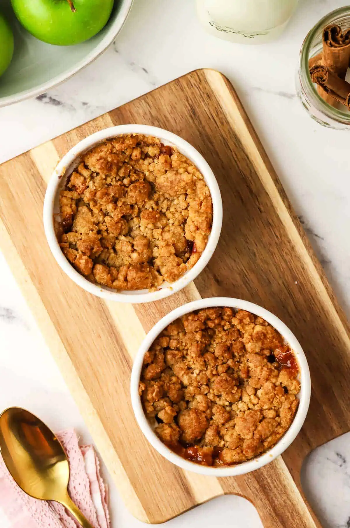 two baked apple crumbles on a cutting board
