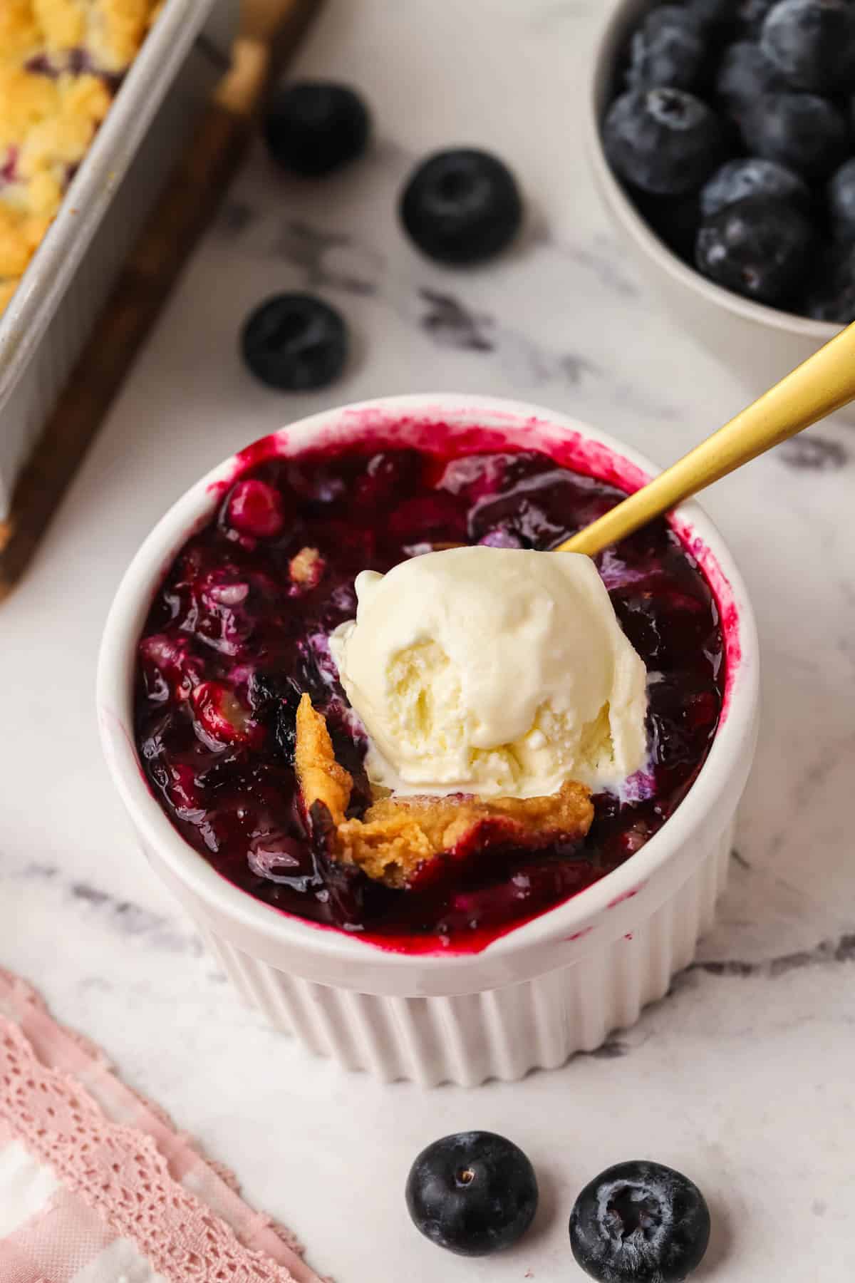 a serving of blueberry crumble in a ramekin topped with ice cream