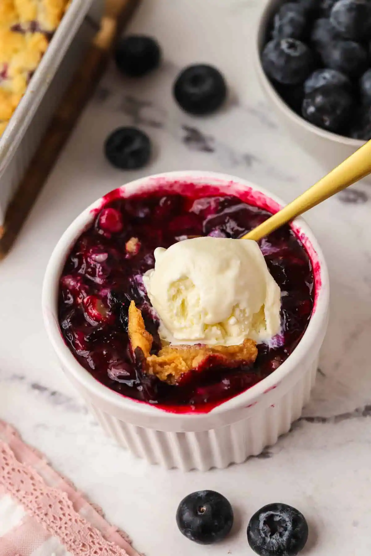 a serving of blueberry crumble in a ramekin topped with ice cream