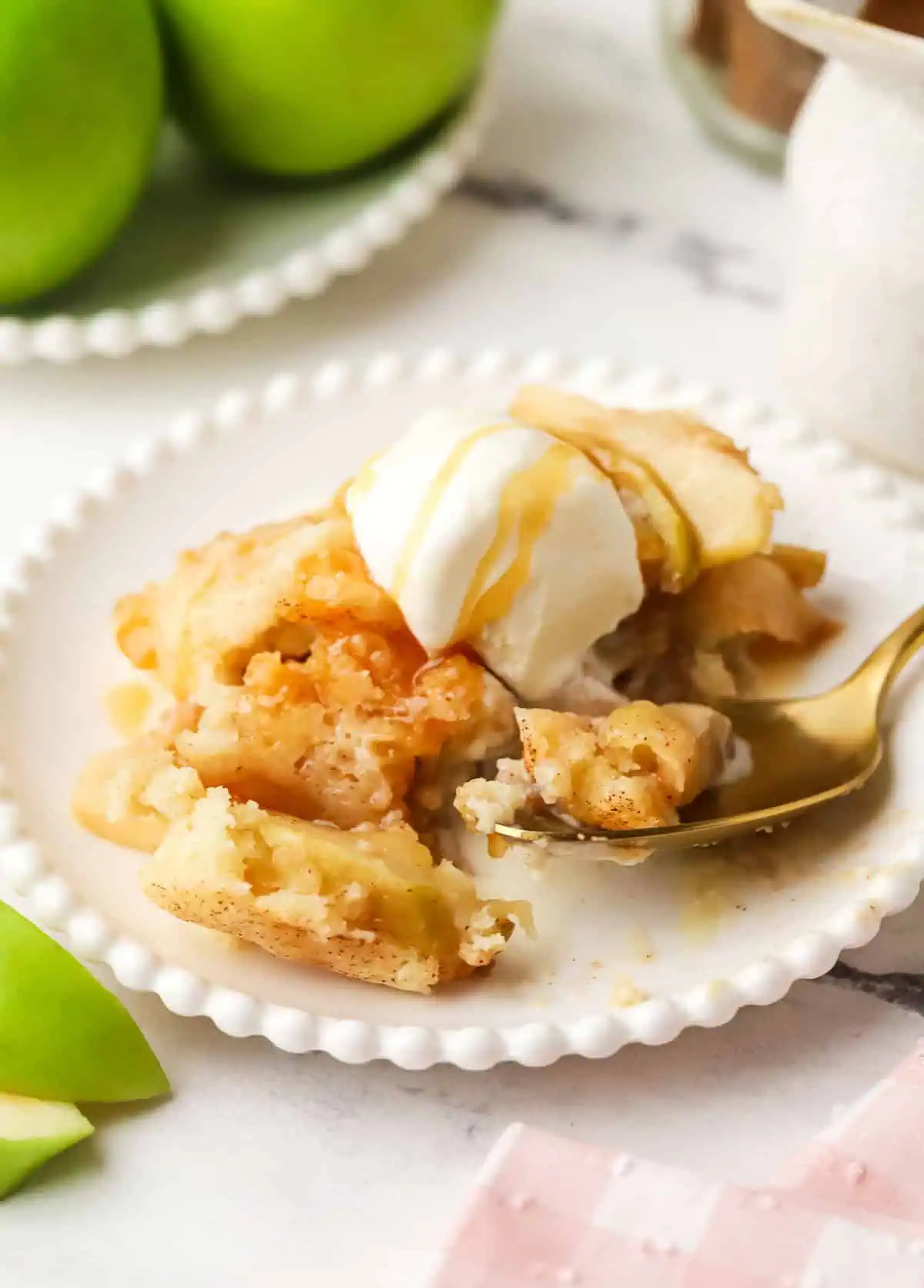 a serving of apple cobbler on a plate topped with ice cream with a spoon