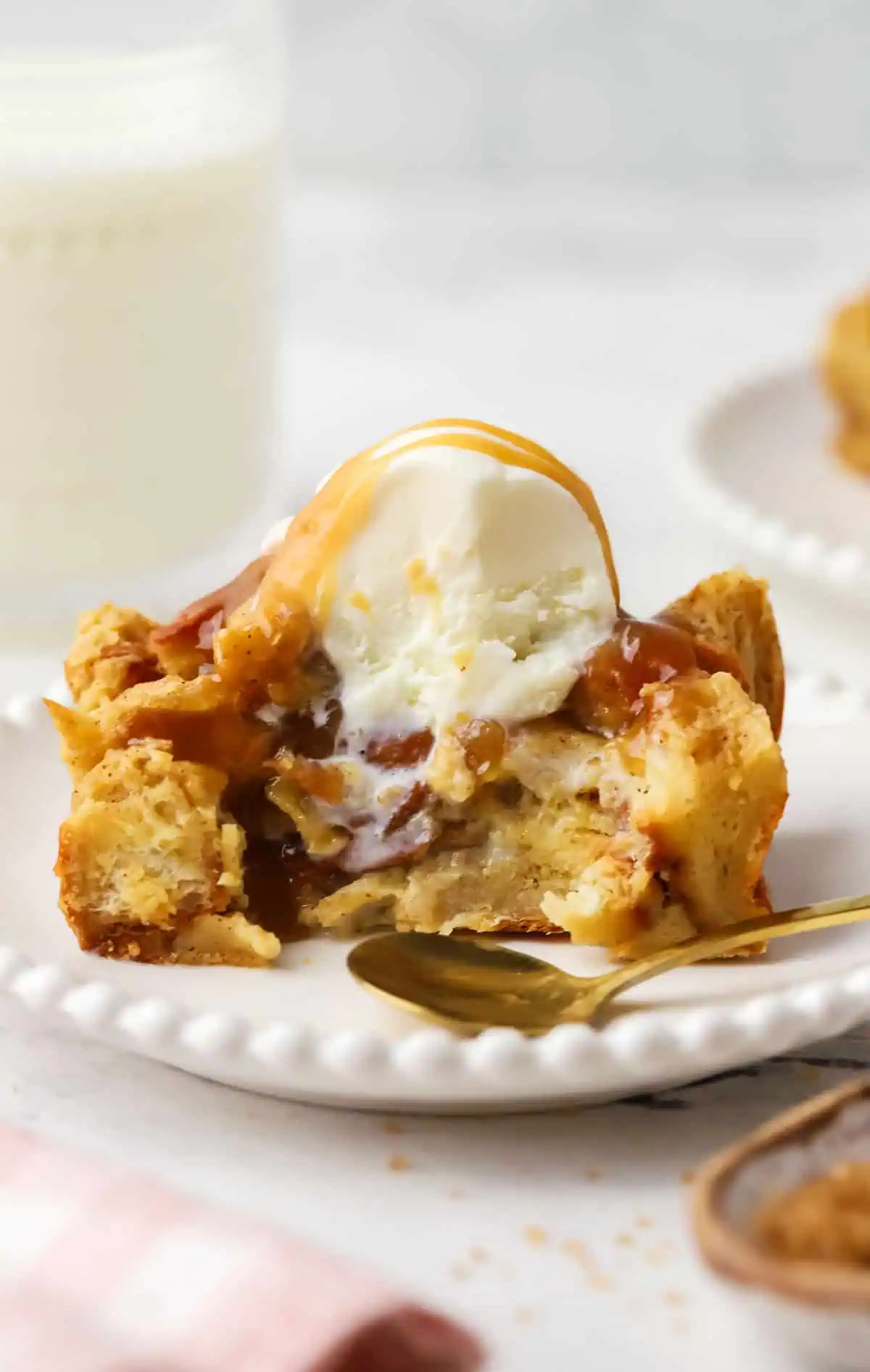 slice of small batch bread pudding topped with ice cream, sauce, and a spoon on the plate
