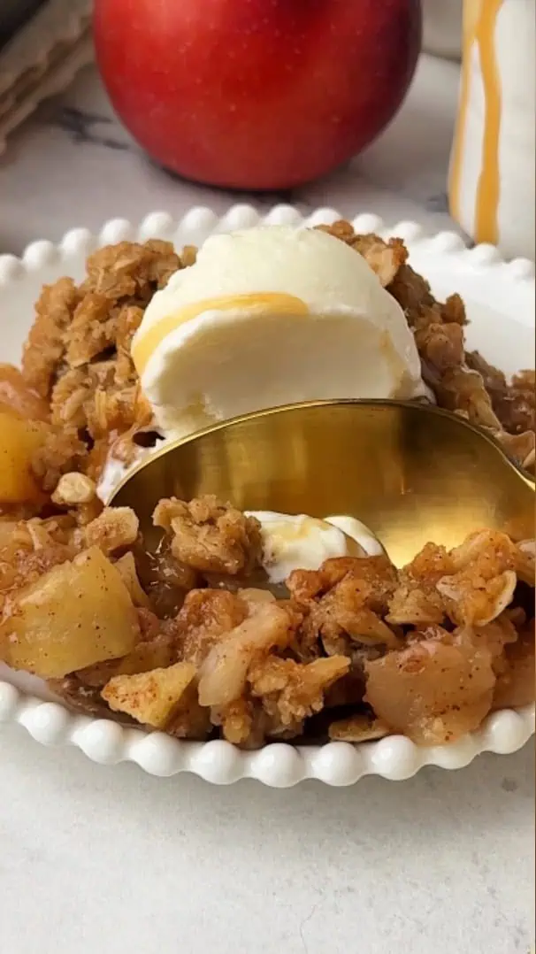 spoon digging into a plate of apple crisp