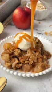 plate of apple crisp topped with caramel and ice cream