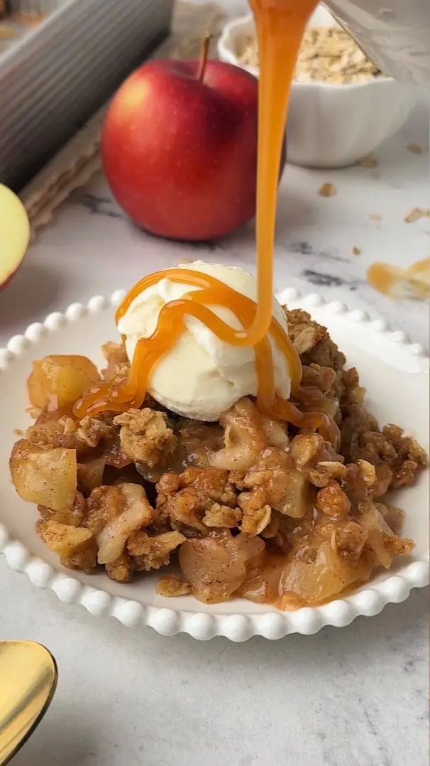plate of apple crisp topped with caramel and ice cream