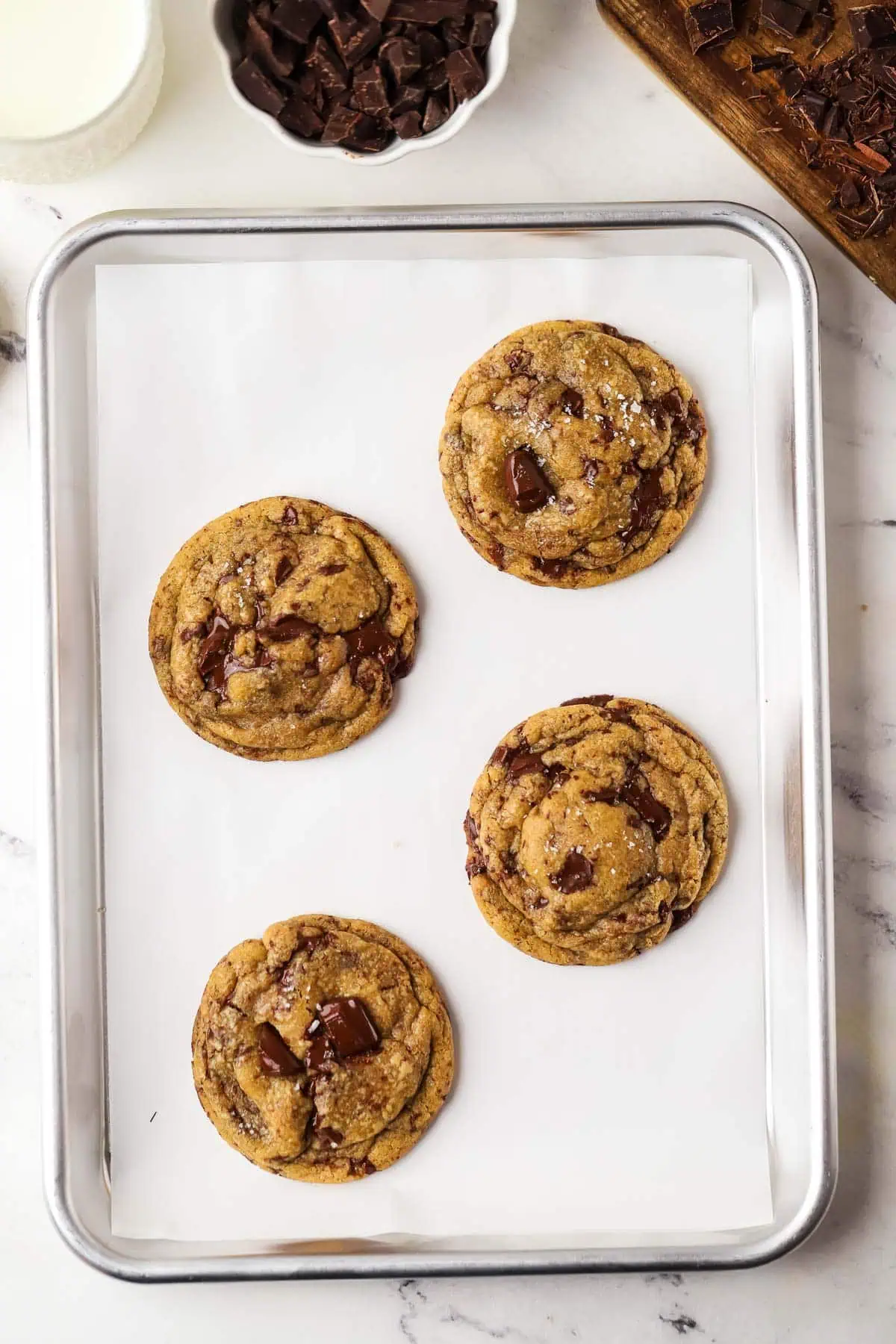 four baked brown butter chocolate chip cookies on a cookie sheet