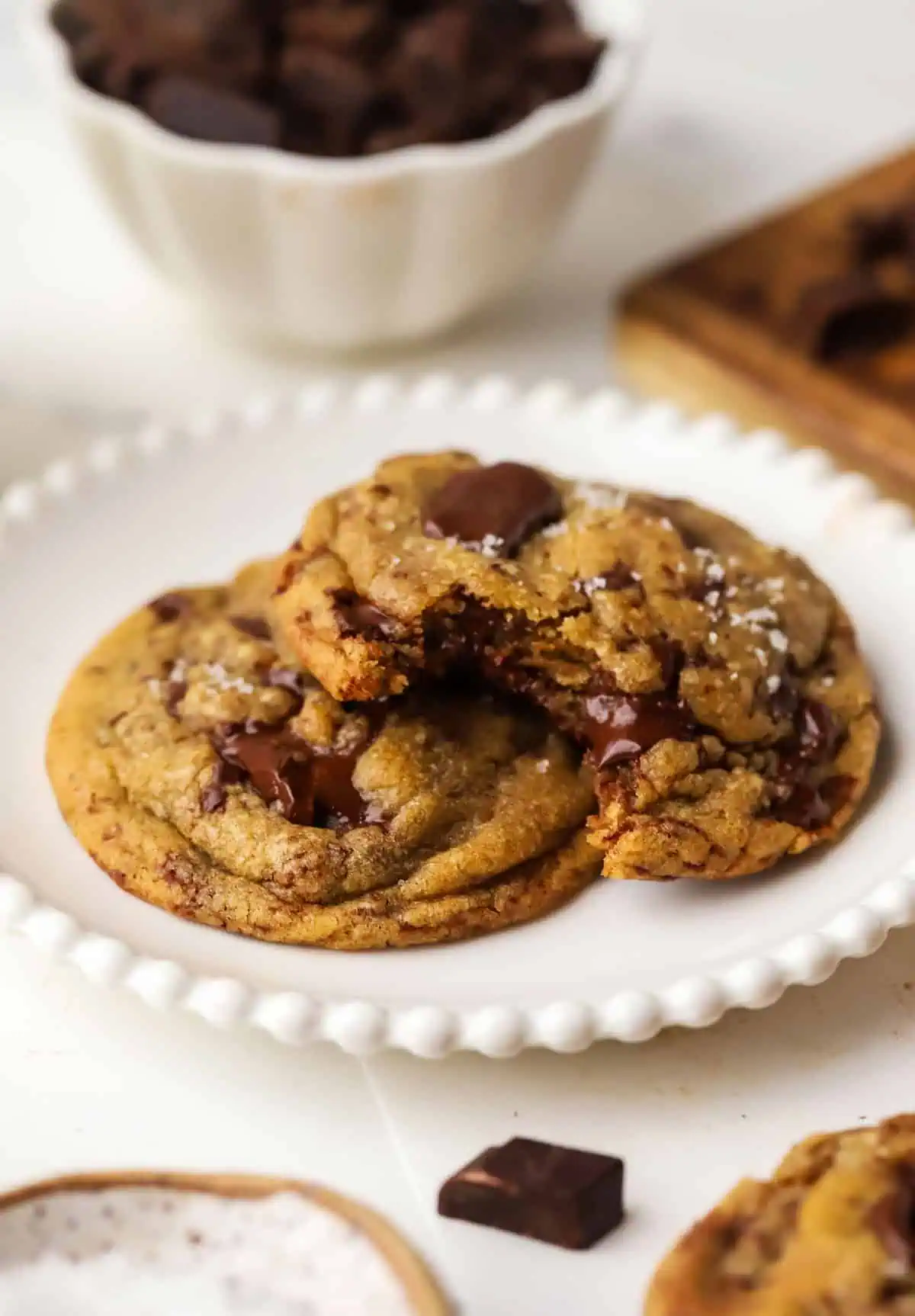two small batch brown butter chocolate chip cookies on a plate with one cookie has a bite taken out of it