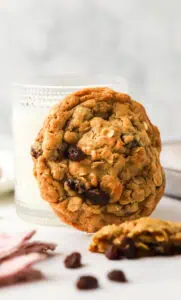 oatmeal raisin cookie leaning against a cup of milk