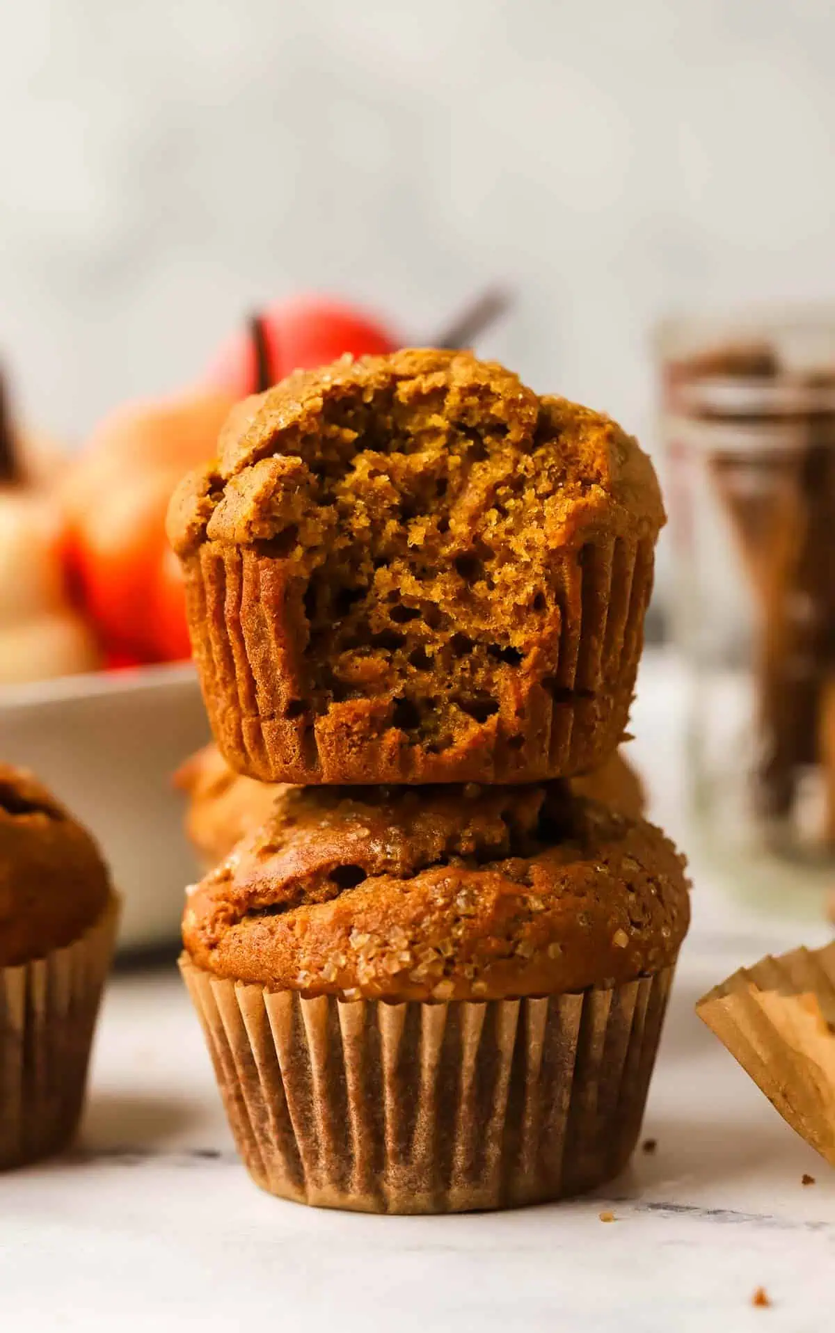 two pumpkin muffins stacked with the top muffin has a bite taken out of it