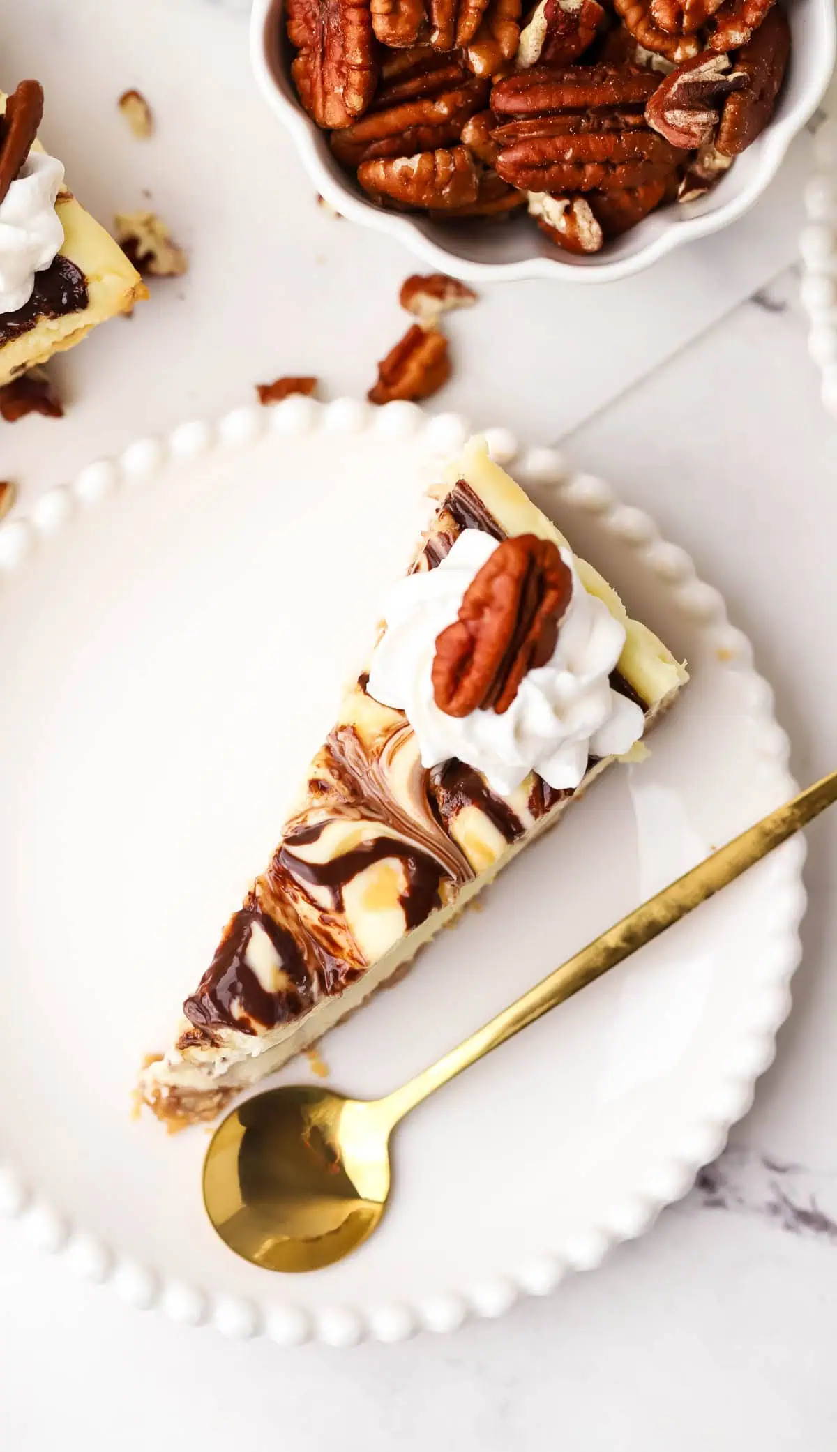 top down view of a slice of turtle cheesecake on a plate with a spoon